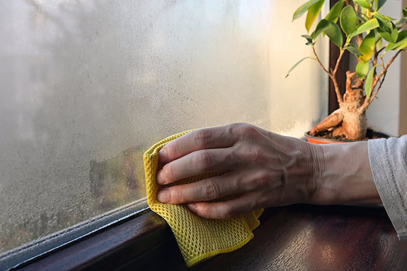 hand wiping condensation off of a window.